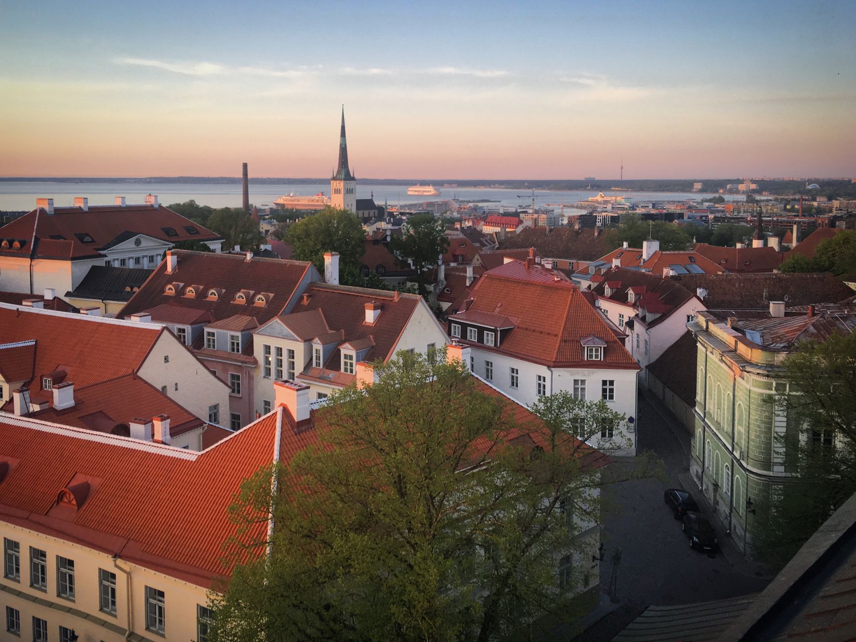 Røde tage og et kirketårn i en gammel by med havet i baggrunden